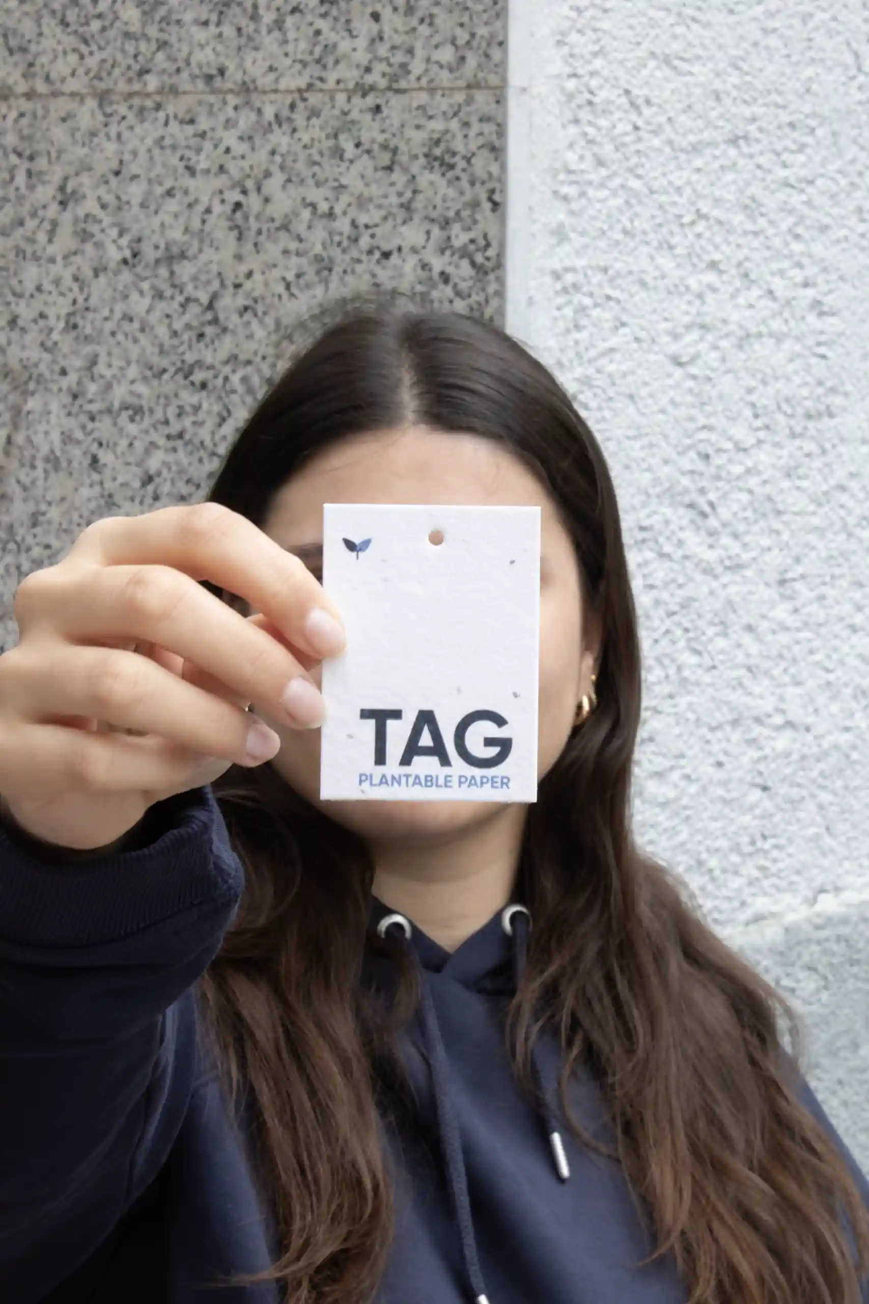 Chica mostrando a cámara una etiqueta de ropa impresa en papel plantable