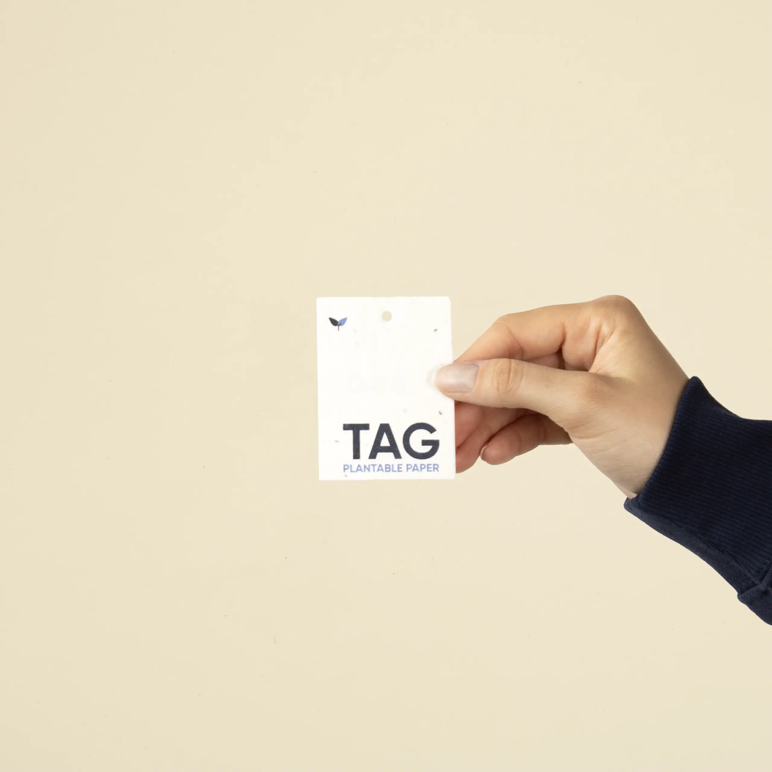 Mano mostrando una etiqueta de ropa impresa en papel plantable