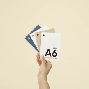 Una mano sujetando cuatro dípticos A6 impresos en papel ecológico