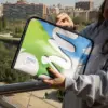 Chica en la calle abriendo una funda de portátil personalizada hecha con lona reciclada, con la ciudad de fondo