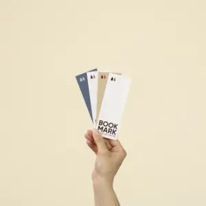 Una mano sujetando cuatro marcapáginas de papel ecológico