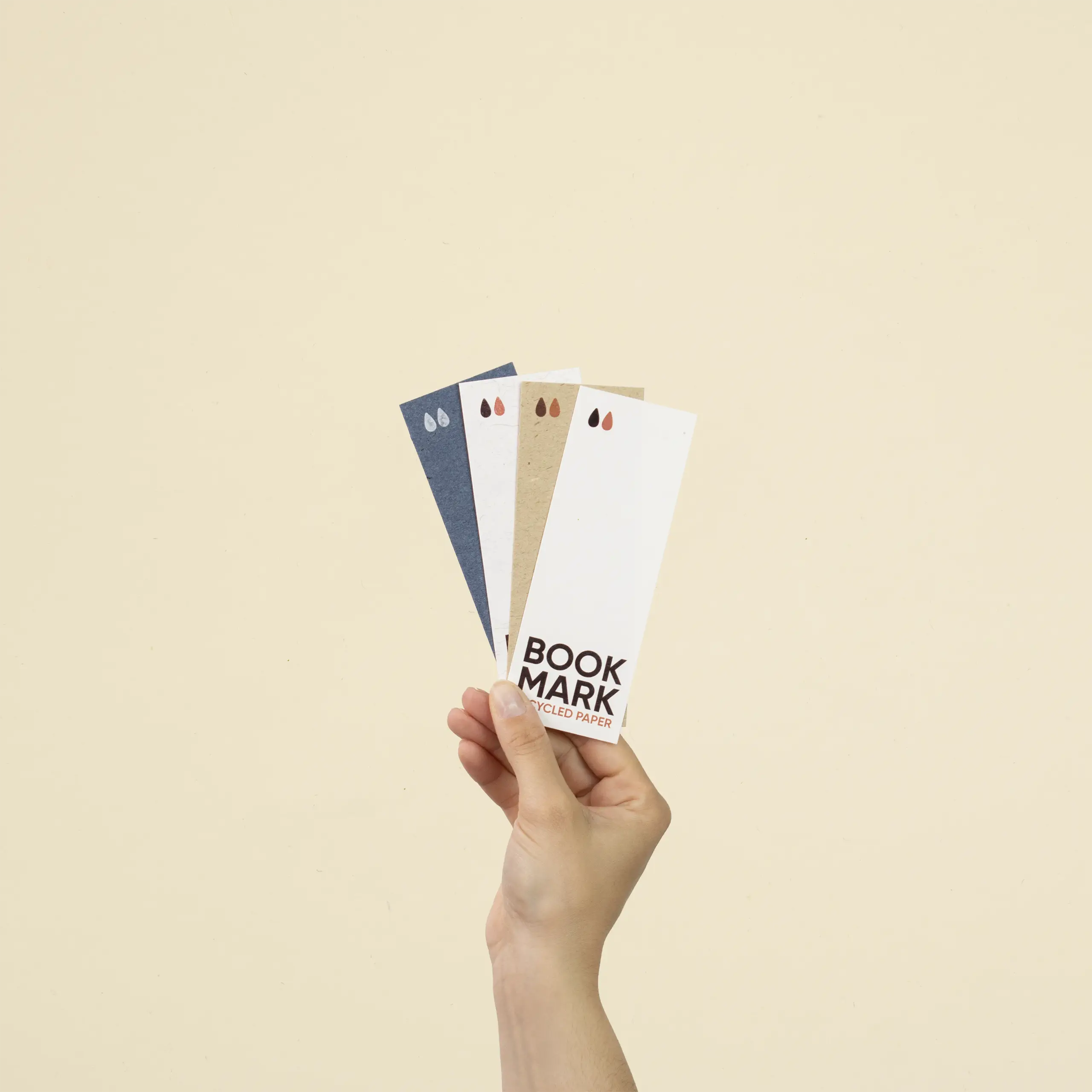 Una mano sujetando cuatro marcapáginas de papel ecológico