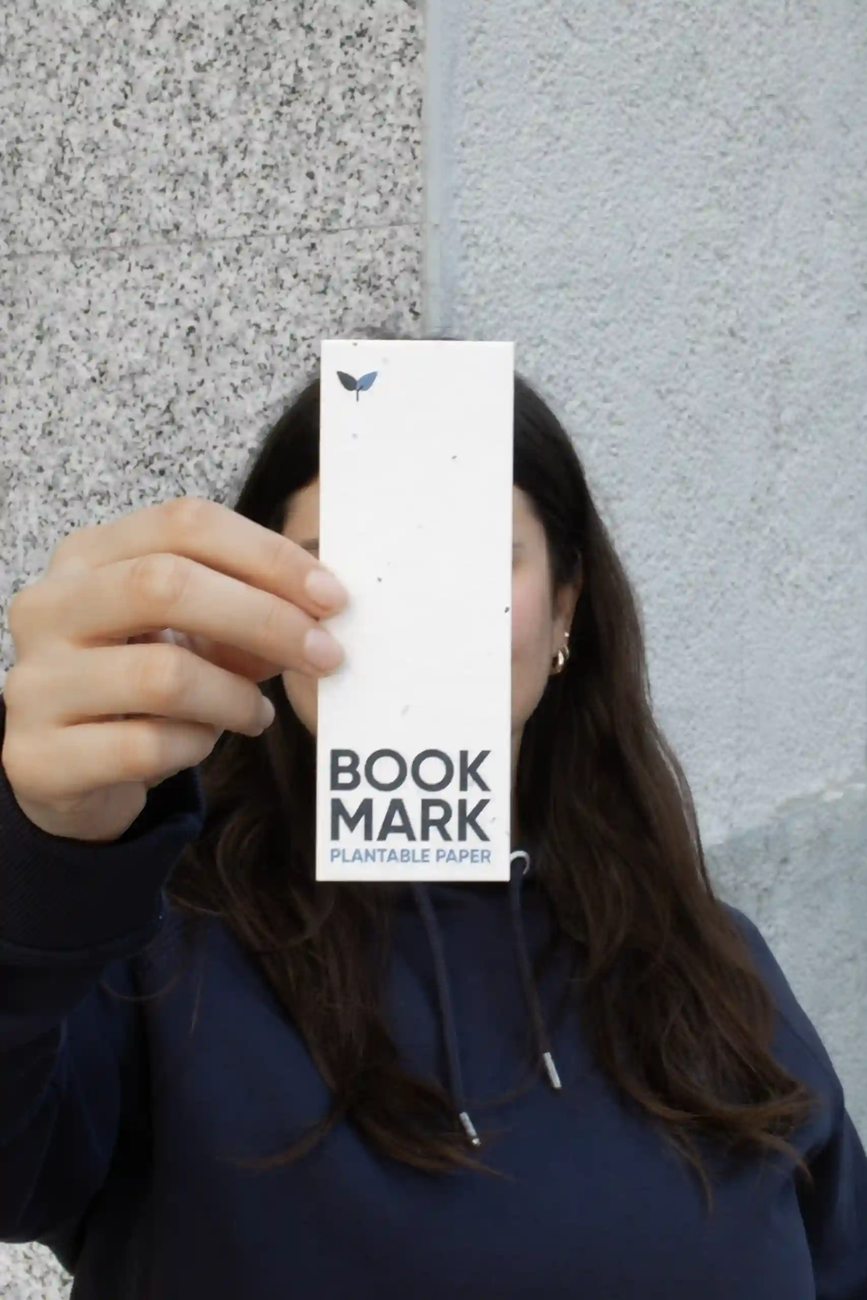 Chica mostrando a la cámara un marcapáginas de papel plantable personalizado