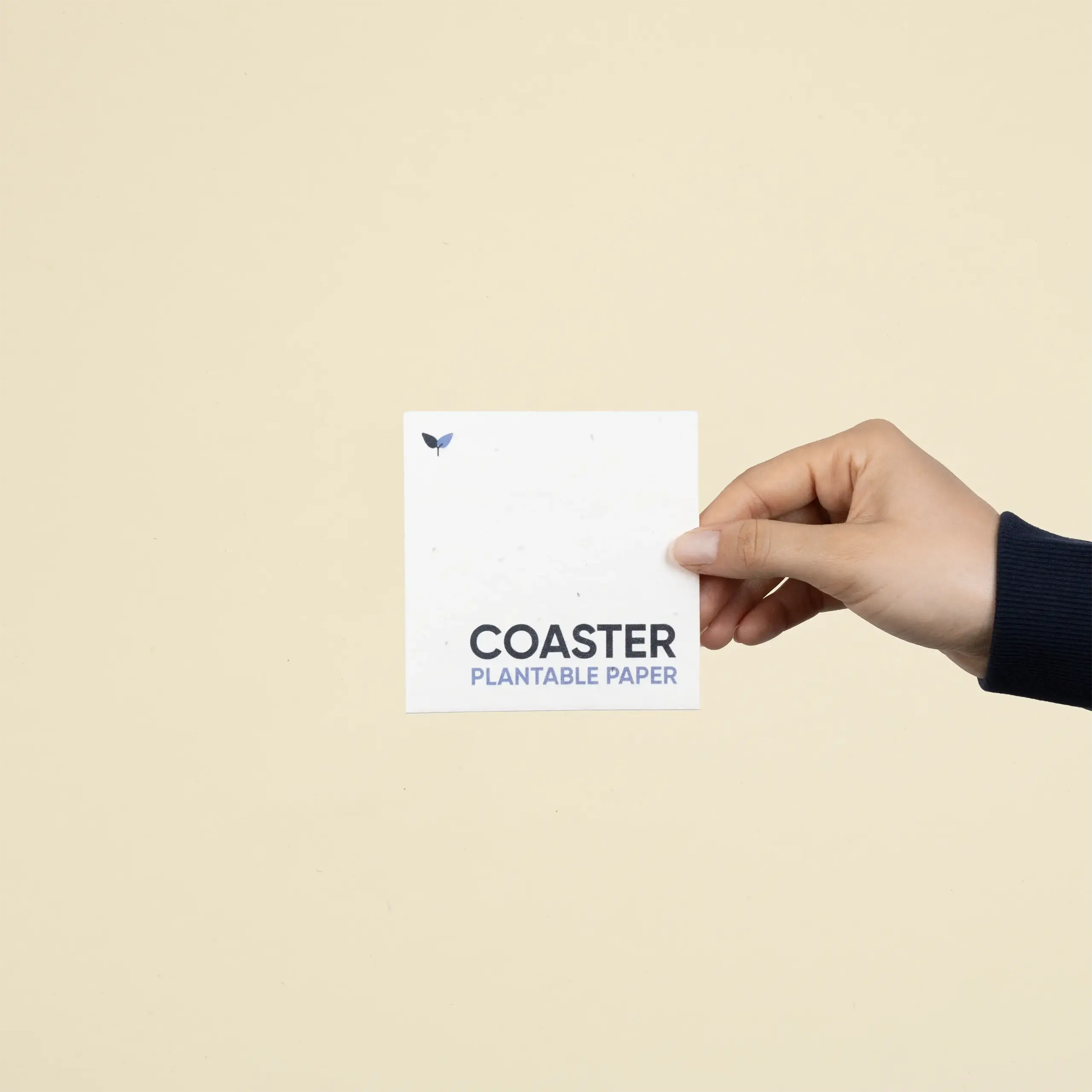 Una mano mostrando un posavasos de papel plantable personalizado