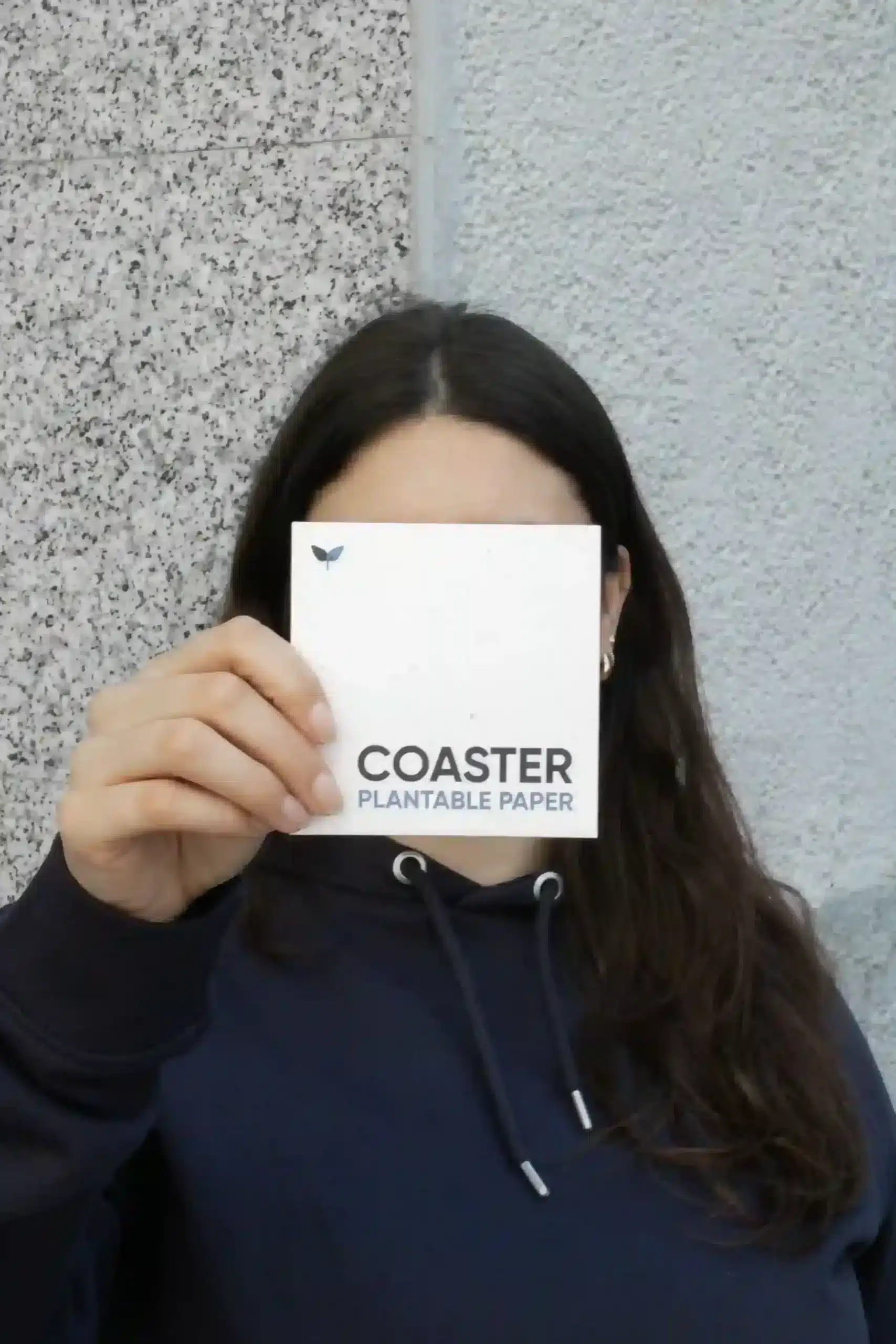 Chica mostrando a la cámara un posavasos de papel plantable personalizado