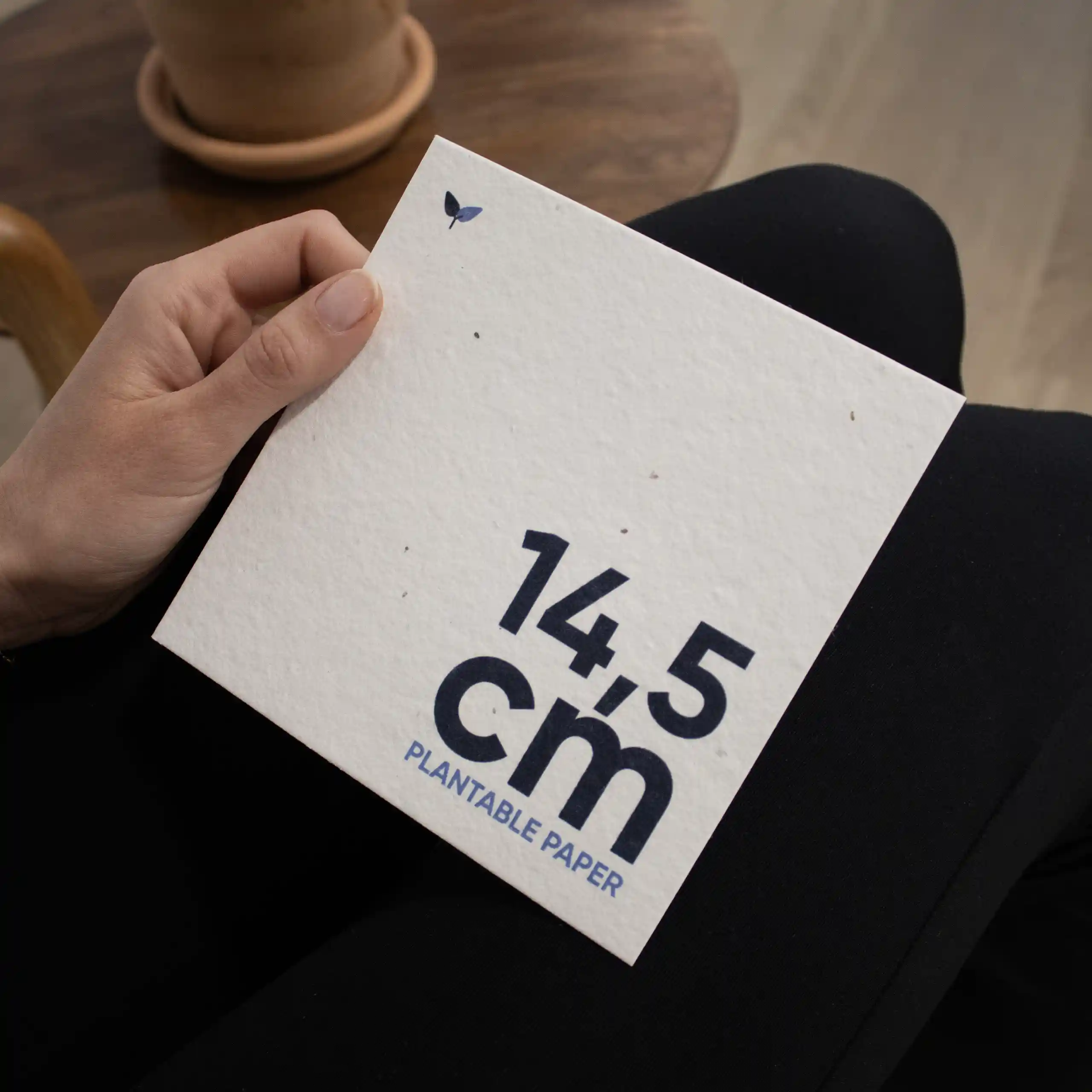 Una mano sujetando una tarjeta cuadrada impresa en papel plantable