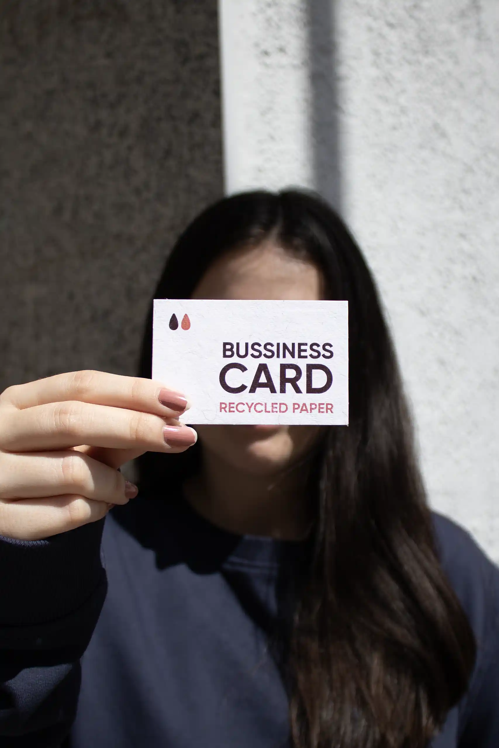 Chica mostrando a cámara una tarjeta de visita impresa en papel ecológico