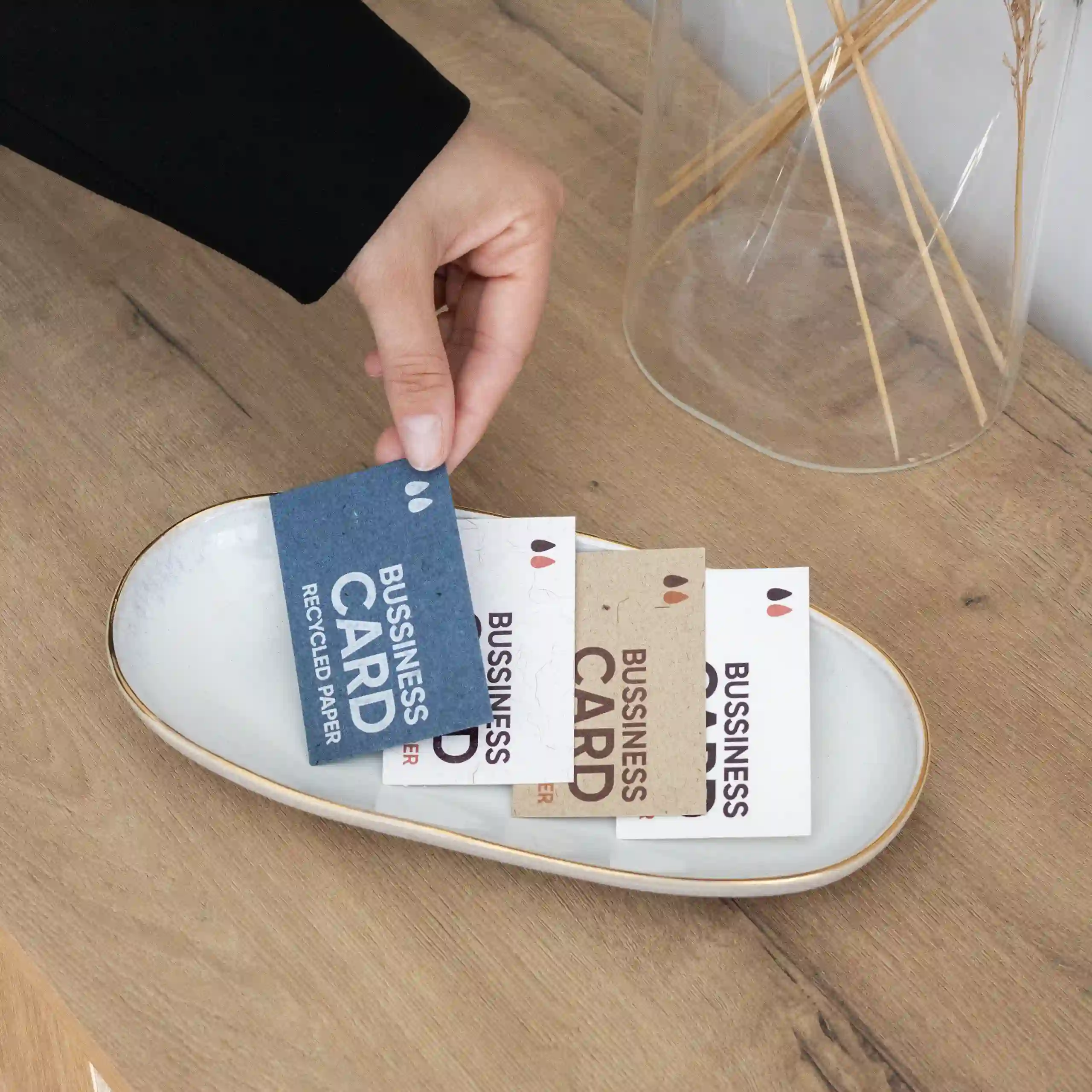 Tarjeta de visita ecológica Mano colocando cuatro tarjetas de visita impresas en papeles ecológicos sobre una bandeja