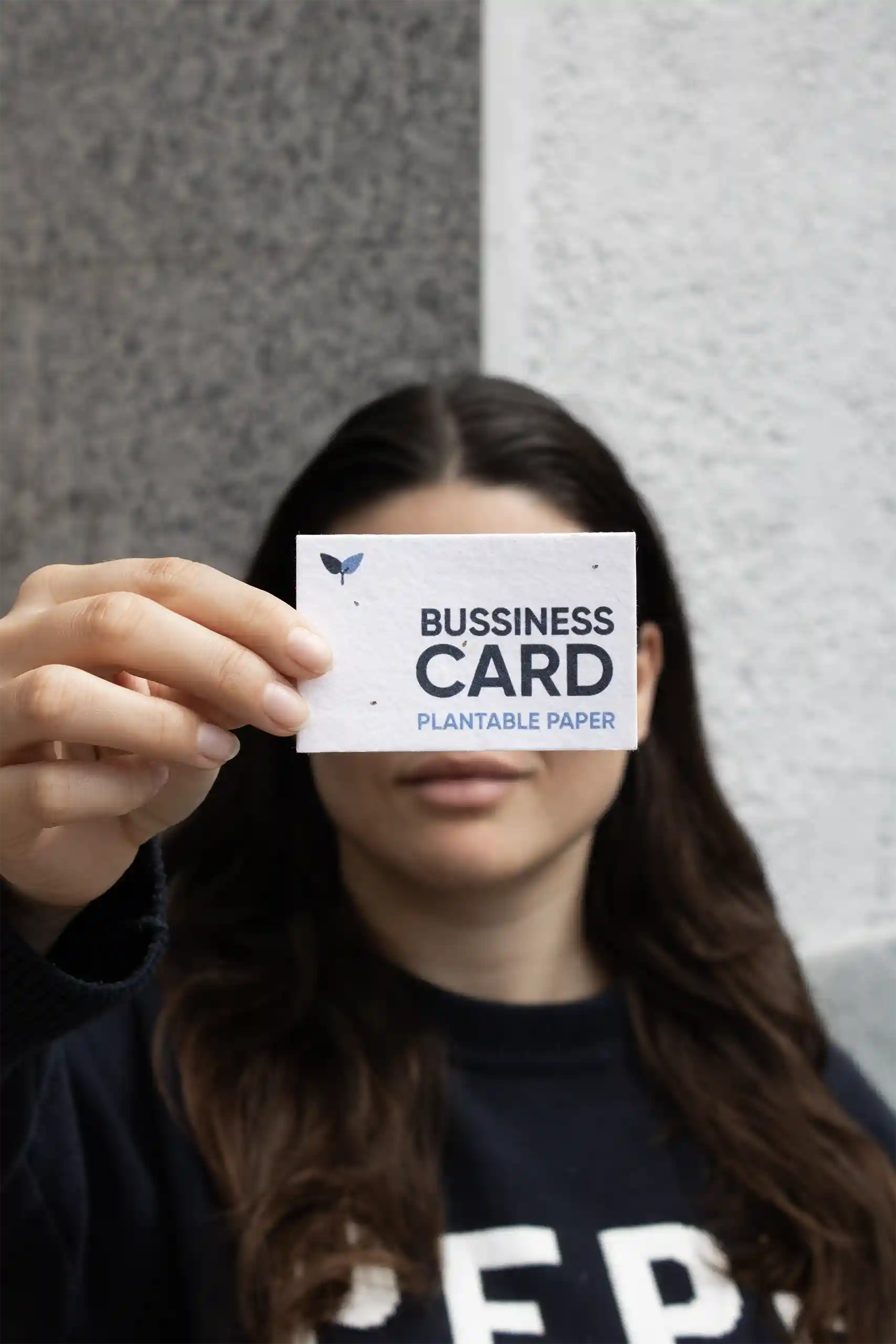 Chica mostrando a cámara una tarjeta de visita impresa en papel plantable