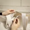 Unas manos cerrando la tote bag de algodón