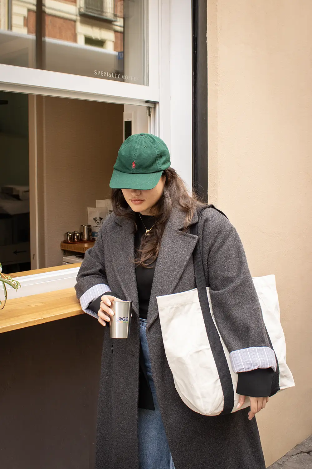 Una chica apoyada en una barra con una tote bag de algodón de asas negras