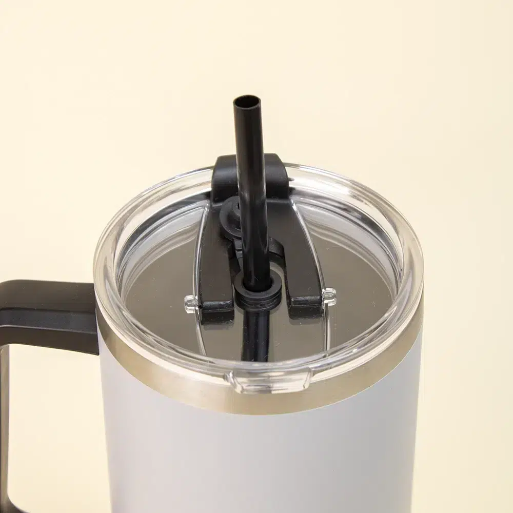 Primer plano de vaso térmico gris de acero inoxidable con pajita sobre un fondo beige