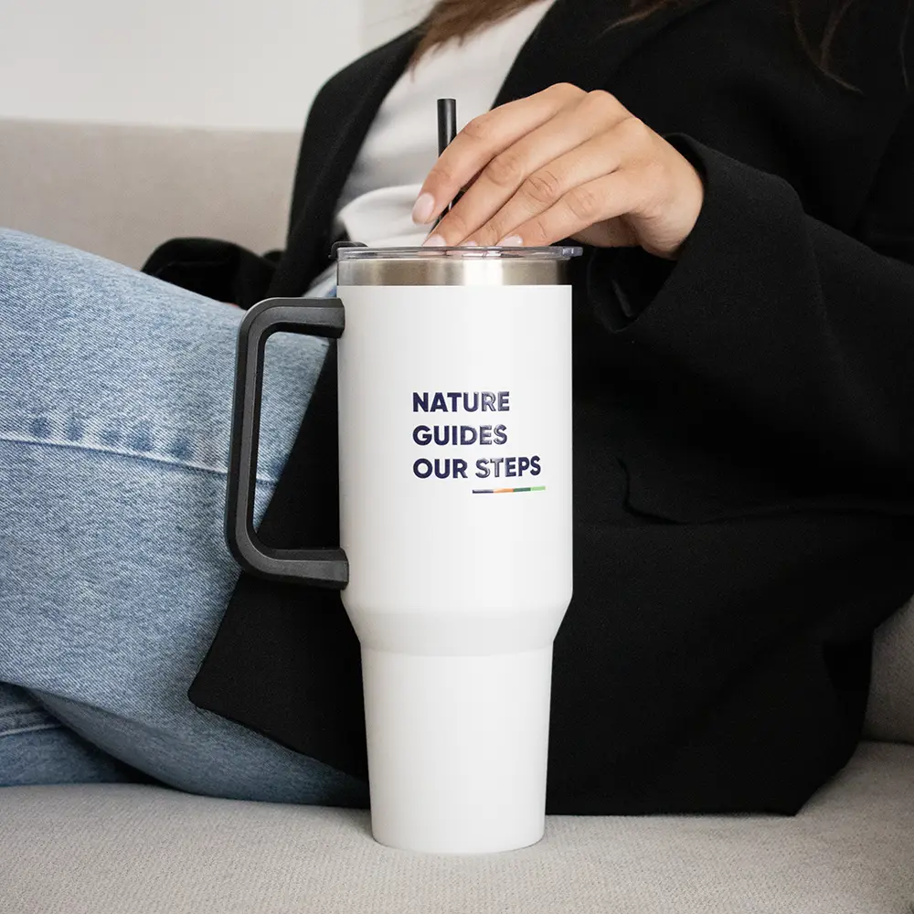 Mano cogiendo la pajita de un vaso térmico de acero inoxidable sobre un sofá