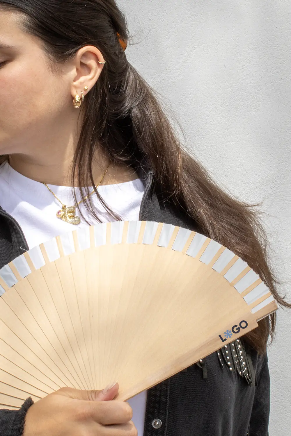 Chica sujetando un abanico de madera y algodón abierto