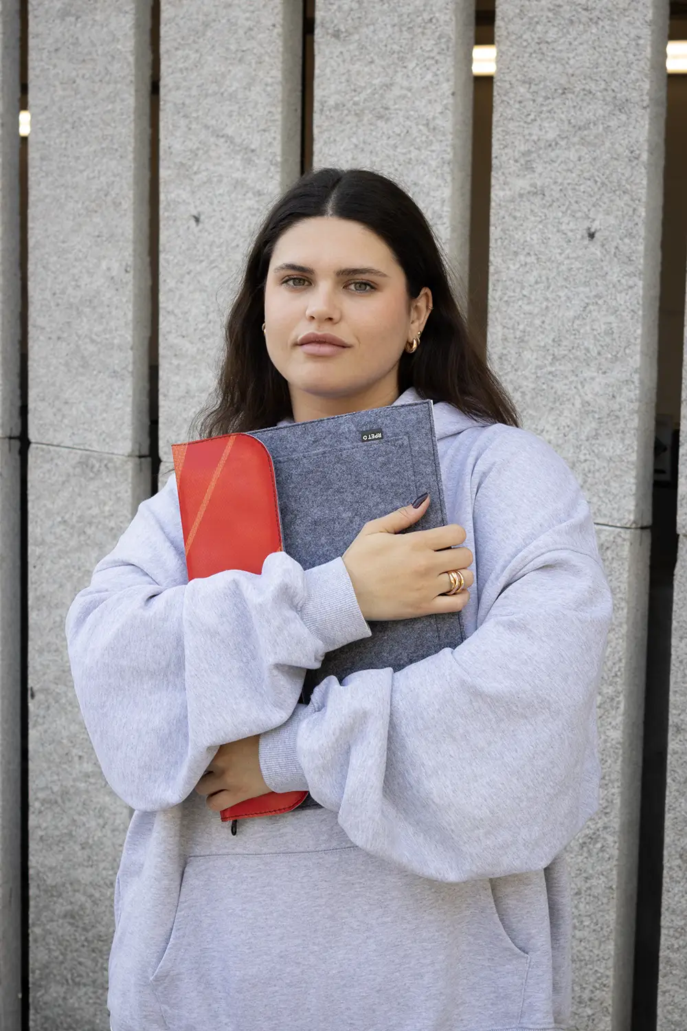 Chica abrazando una funda de portátil personalizada hecha con fieltro y lona roja reciclada