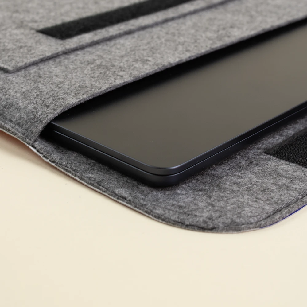 Funda de portátil de fieltro entreabierta con un portátil negro