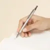 Bolígrafo de aluminio reciclado GANTE Mano escribiendo sobre un cuaderno con un bolígrafo plateado de aluminio reciclado