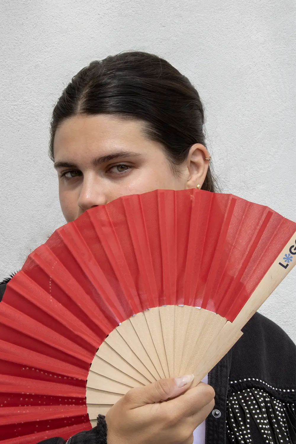 Chica sujetando abanico rojo con varillas de madera y tela poliéster abierto