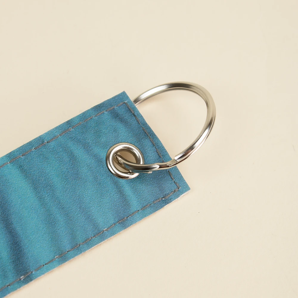 Anilla y ojal metálicos de un llavero azul hecho con lona reciclada
