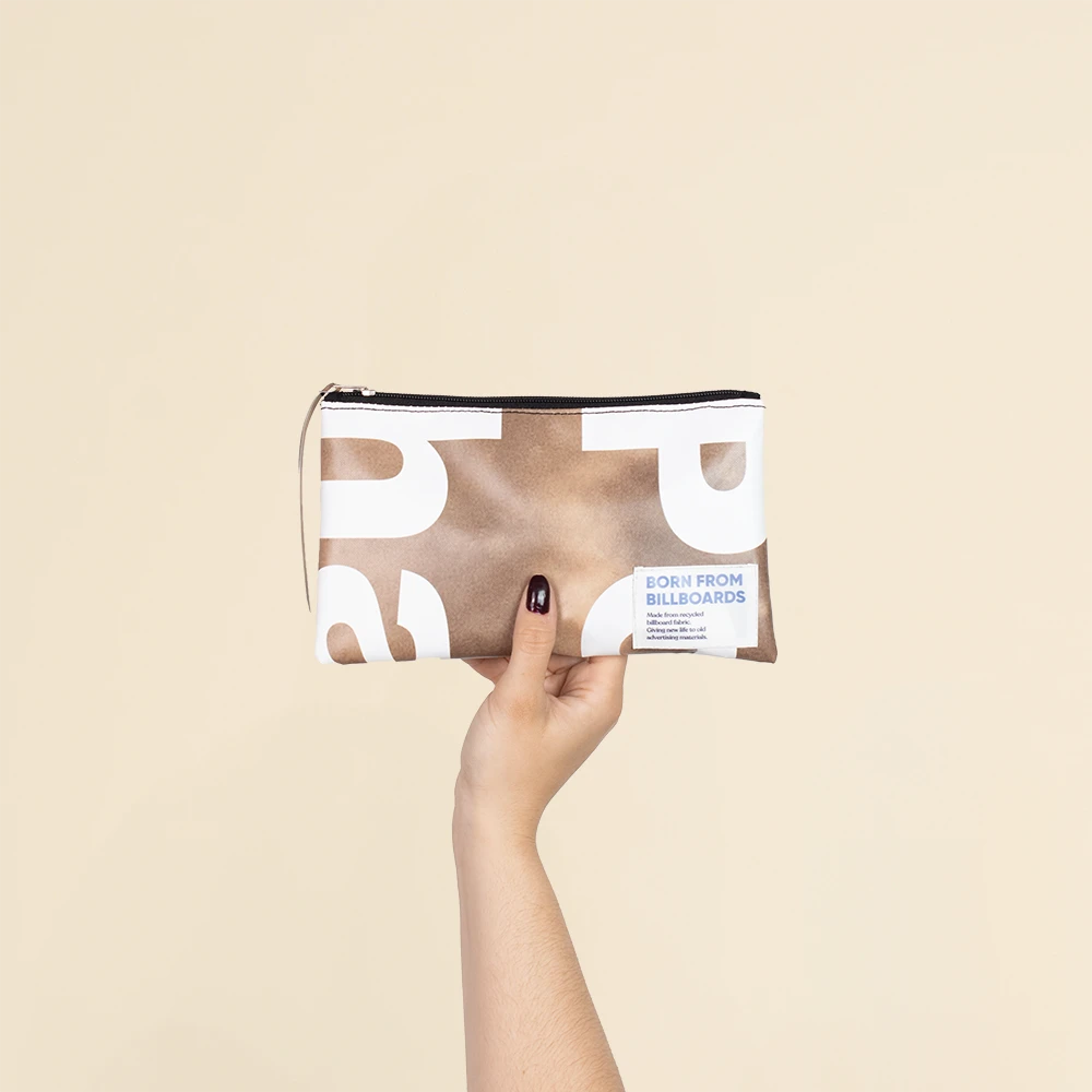 Neceser de lona reciclada MOMO Mano mostrando un neceser de lona reciclada de color marrón y blanco