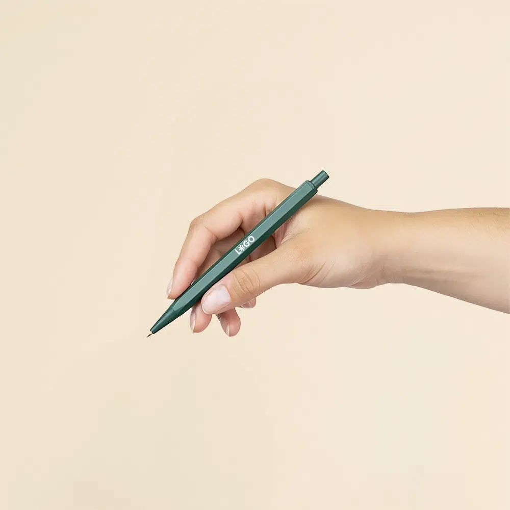 Mano sujetando bolígrafo de aluminio verde sobre un fondo beige