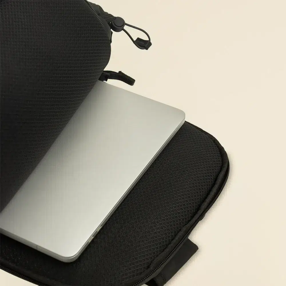 Portátil guardado en mochila abierta urbana personalizada negra sobre un fondo beige