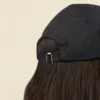 Gorra visera personalizable KAPA Parte trasera de gorra personalizable con visera deportiva sobre un fondo beige