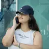 Chica hablando por teléfono con una gorra azul con logo lateral