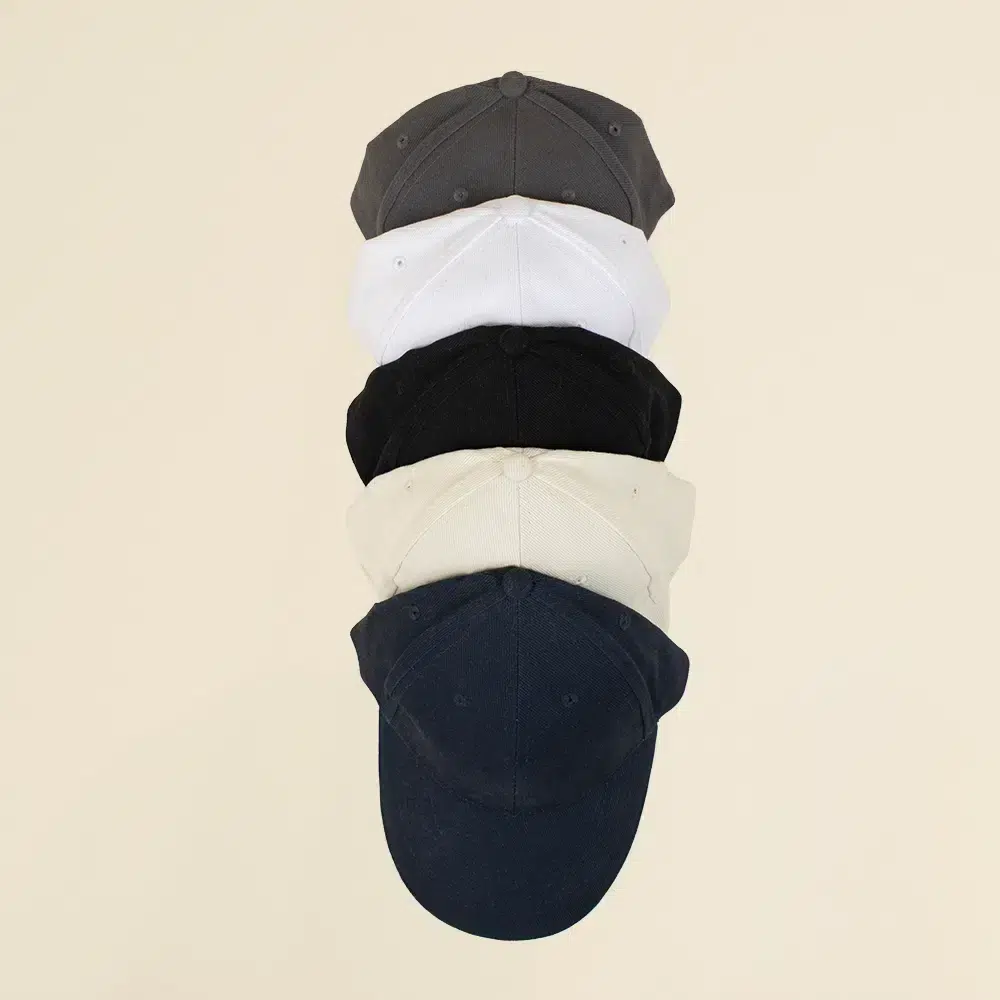 Cinco gorras de colores en fila en un fondo beige