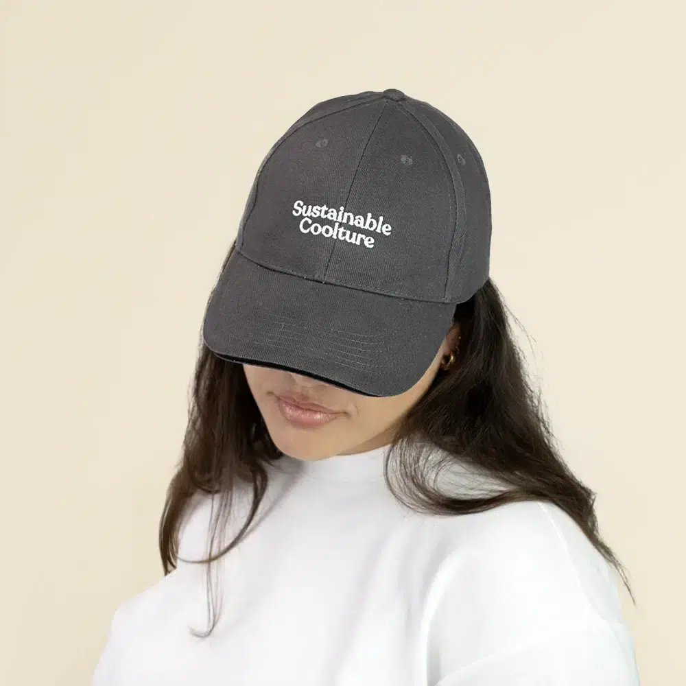 Chica con una gorra gris con logo frontal en un fondo beige