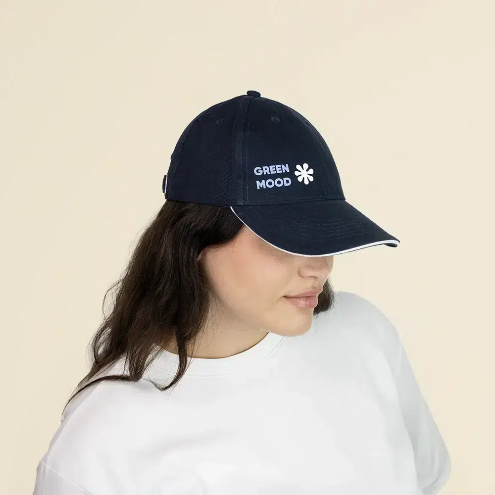 Chica con una gorra azul con logo lateral en un fondo beige