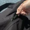 Bolsa de deporte PULSE Mano cerrando la cremallera de una bolsa de deporte negra de poliƩster reciclado