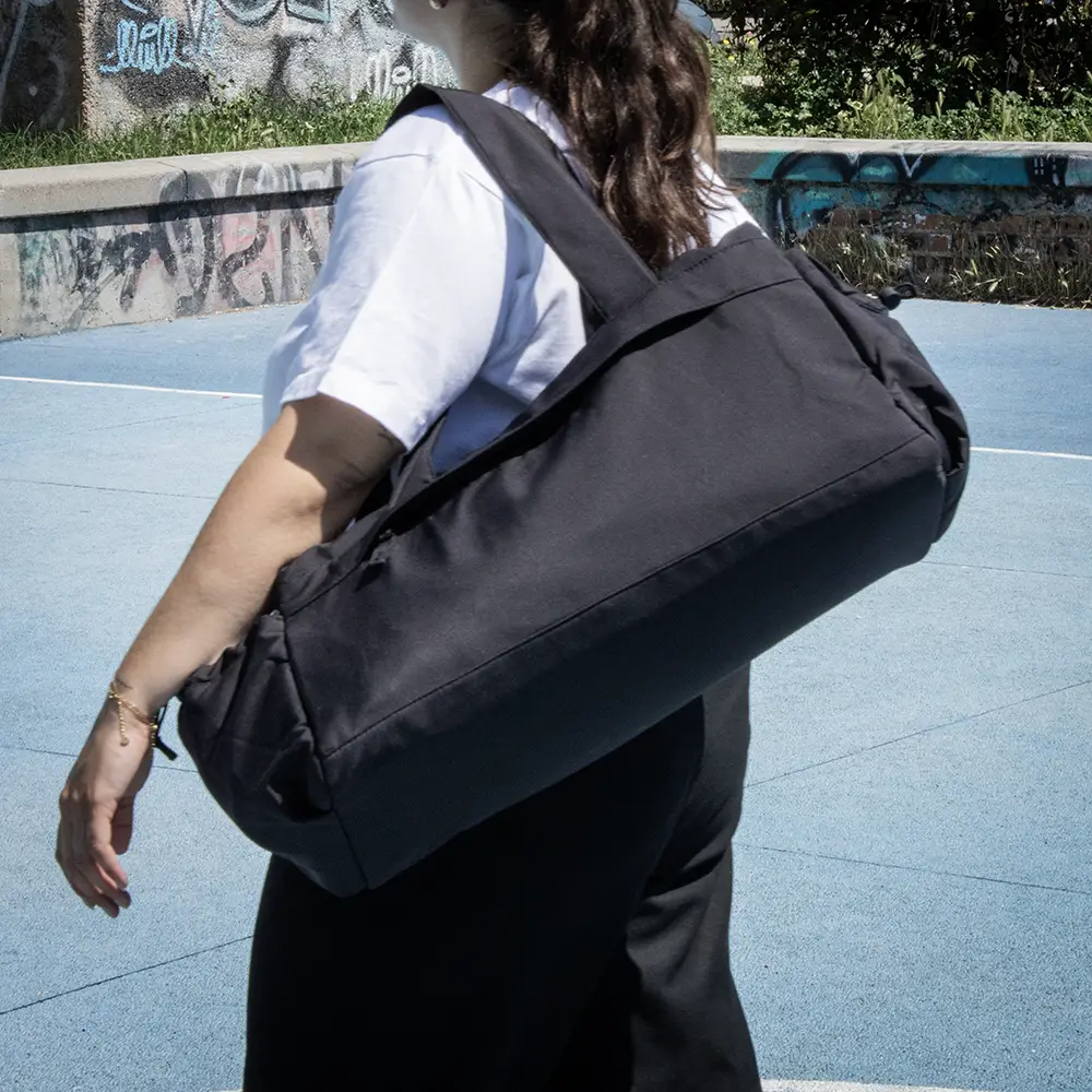 Chica con una bolsa de deporte negra de poliéster reciclado