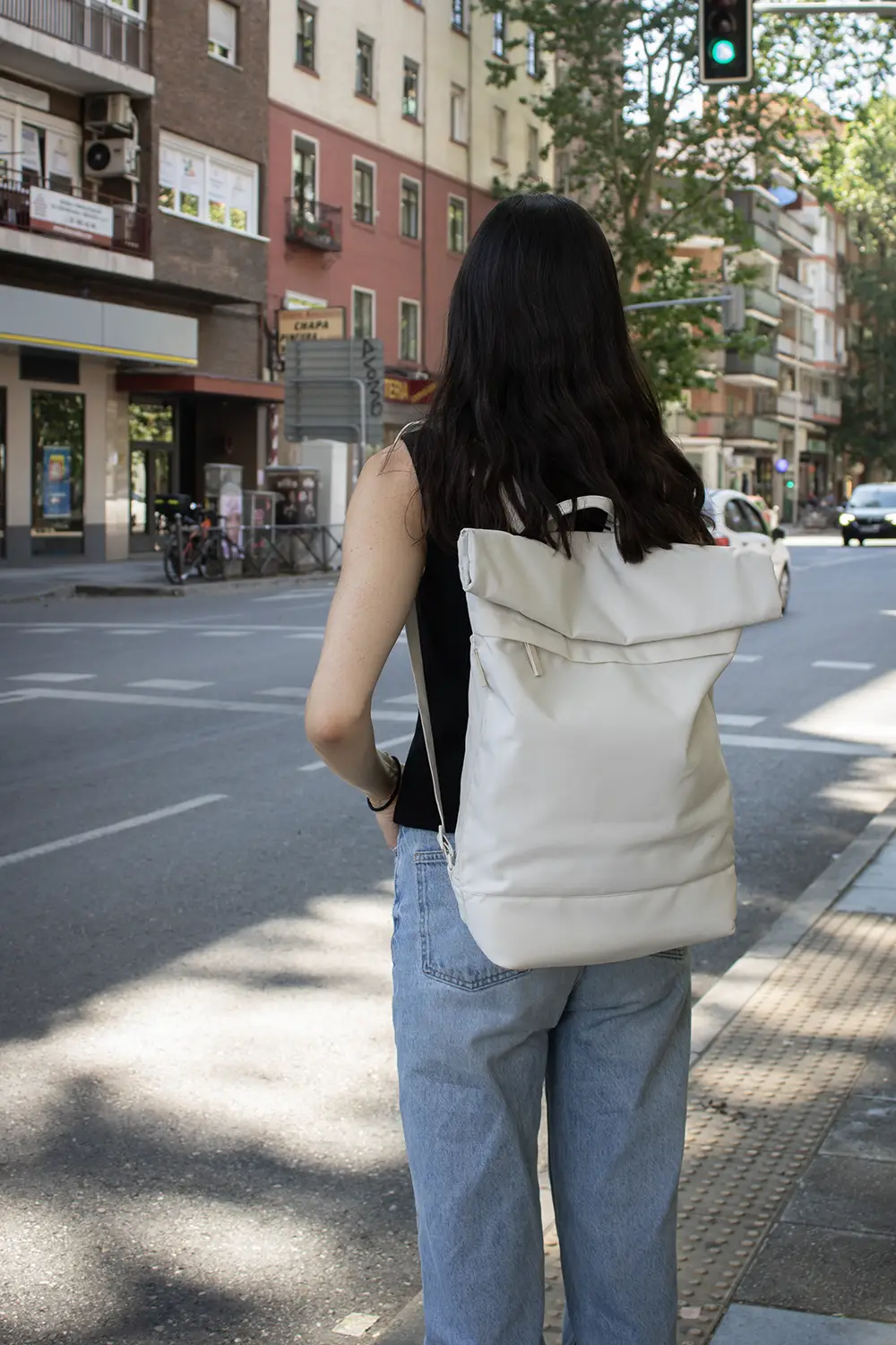 Chica al cruzar la calle con una mochila roll top personalizada blanca
