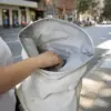 Mano cogiendo algún objeto del interior de una mochila roll top personalizada blanca