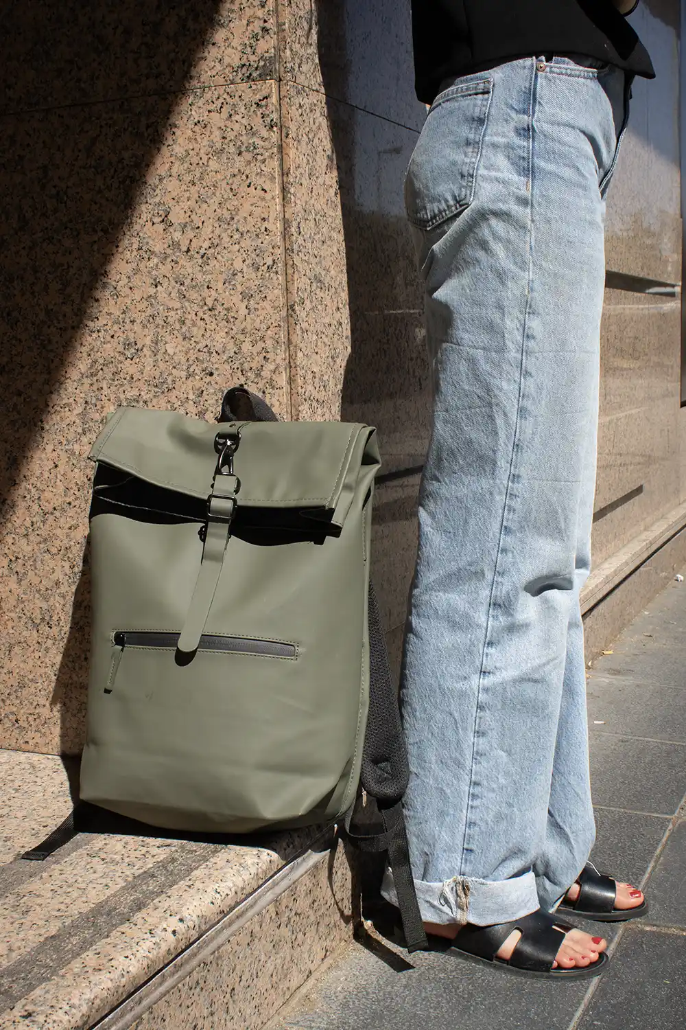 Piernas de chica junto con mochila reciclada con cierre roll top sobre un escalón