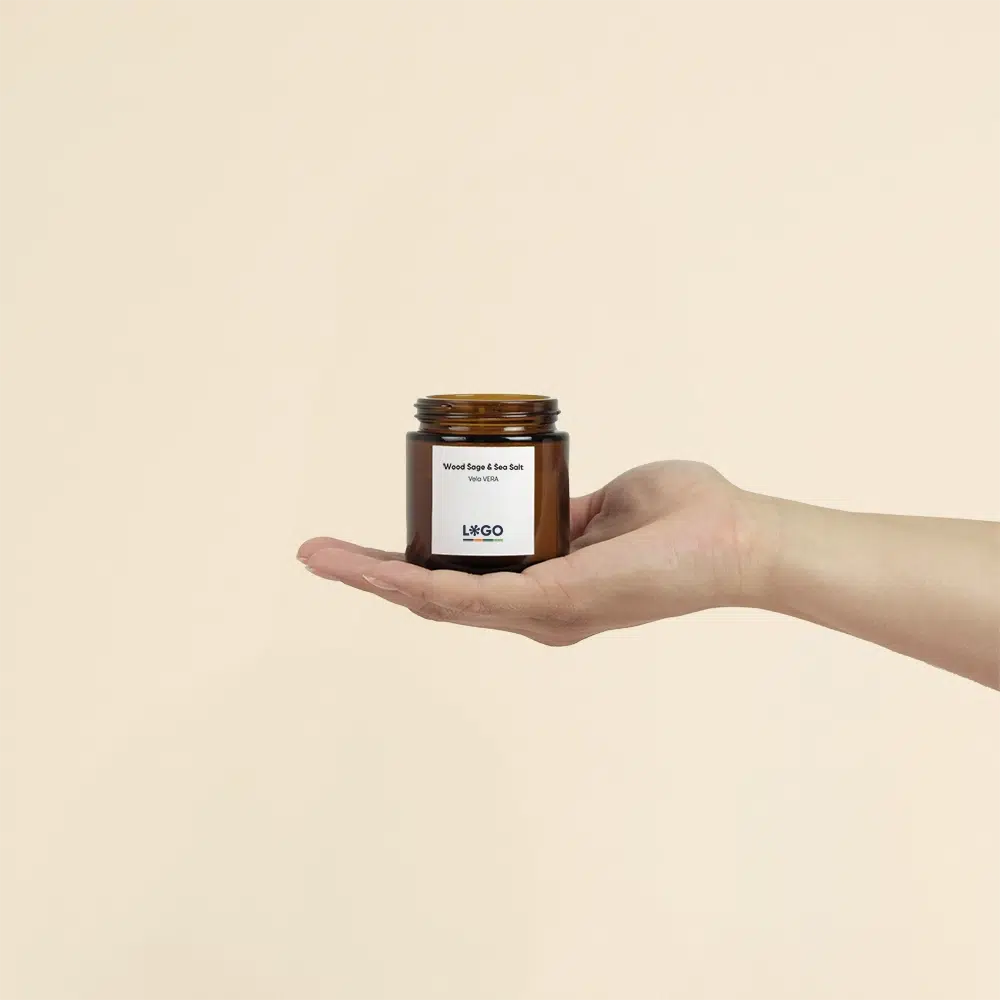 Mano sosteniendo vela aromática personalizada sobre un fondo beige