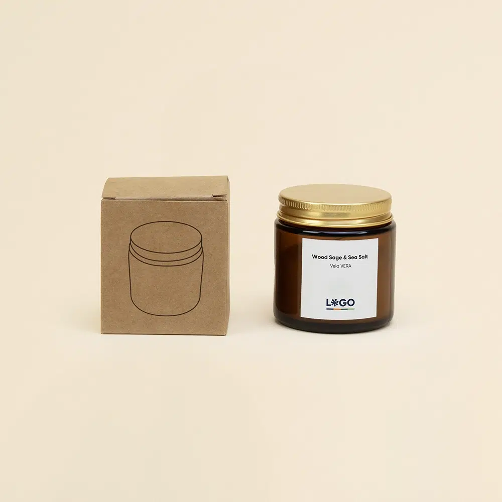 Vela aromática personalizada con tapa metálica junto a su packaging sobre un fondo beige