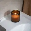 Vela aromática personalizada encendida sobre lavabo de un baño