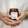Manos sosteniendo y mostrando vela aromática personalizada