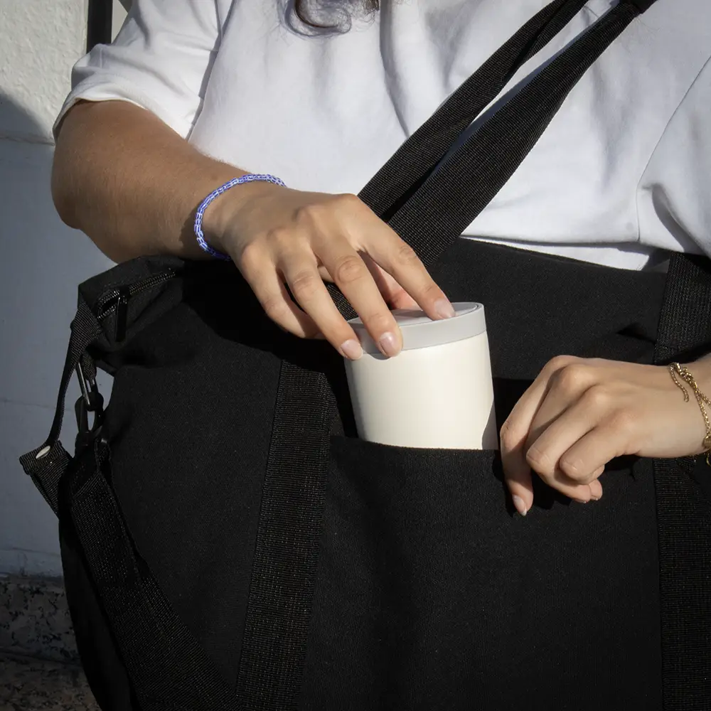 Bolsa de viaje VITA Manos guardando un vaso en una bolsa negra de viaje de algodón y poliéster reciclado