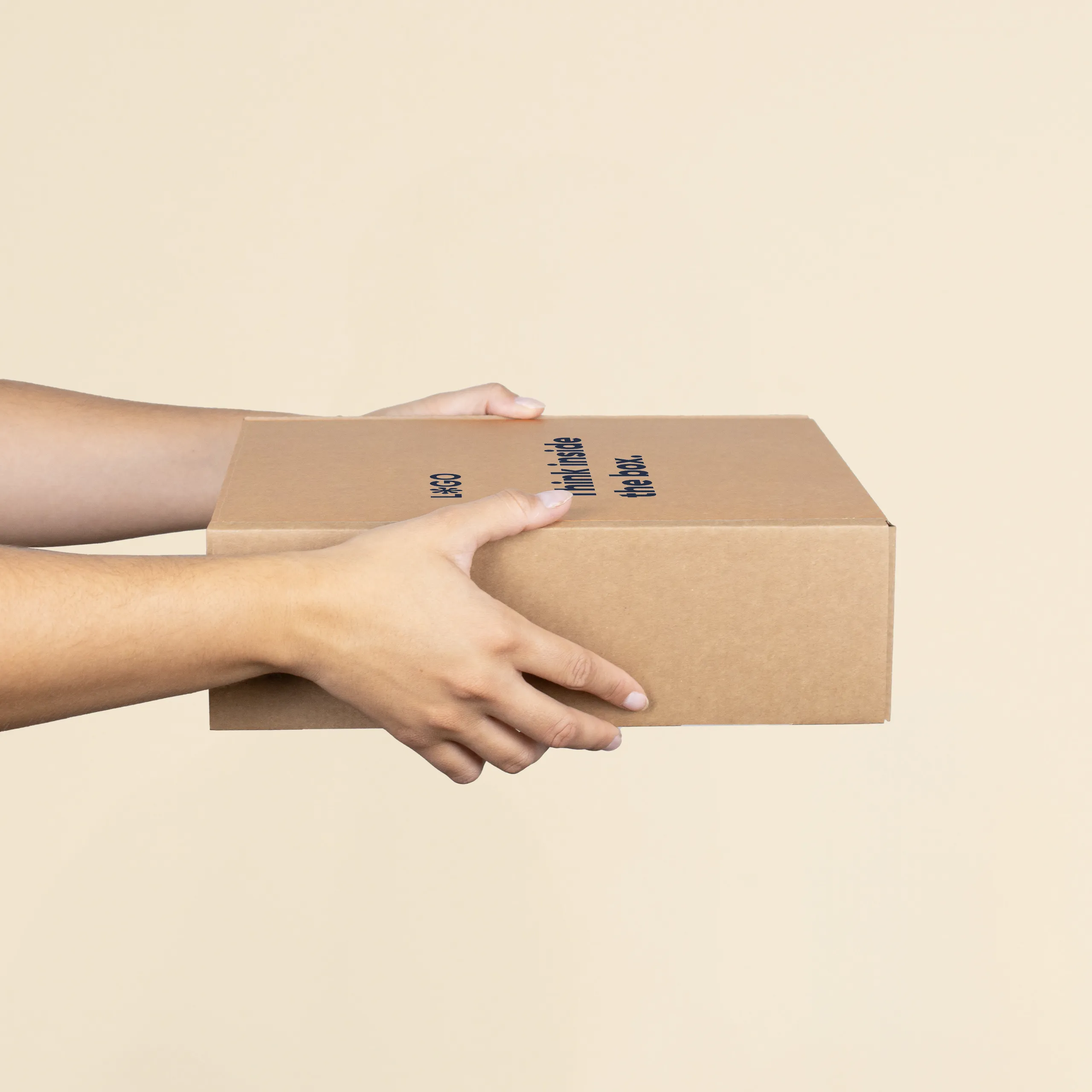Caja M ecológica Manos sosteniendo una caja M personalizada a un color sobre un fondo beige