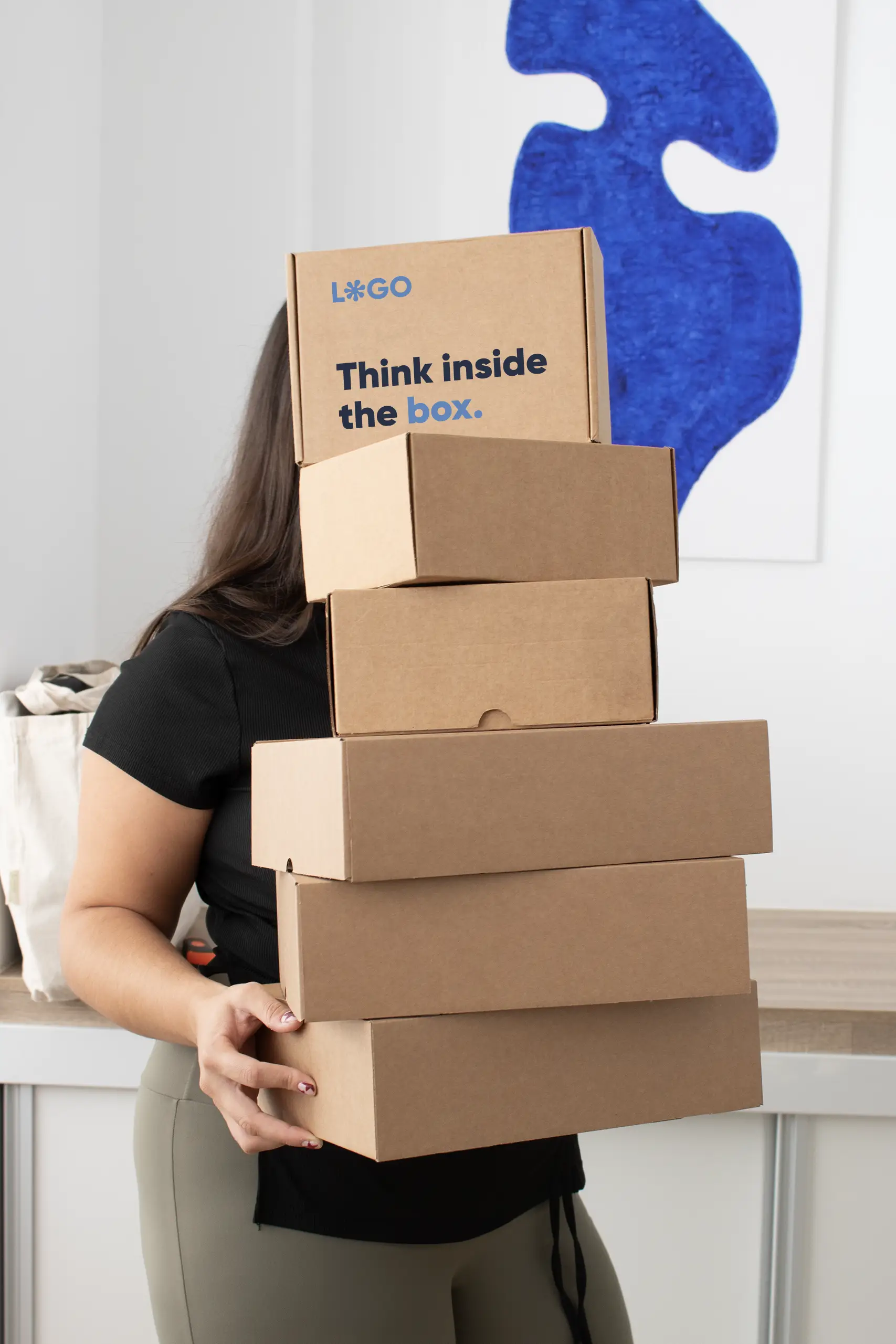 Chica sosteniendo una torre de cajas ecológicas personalizadas