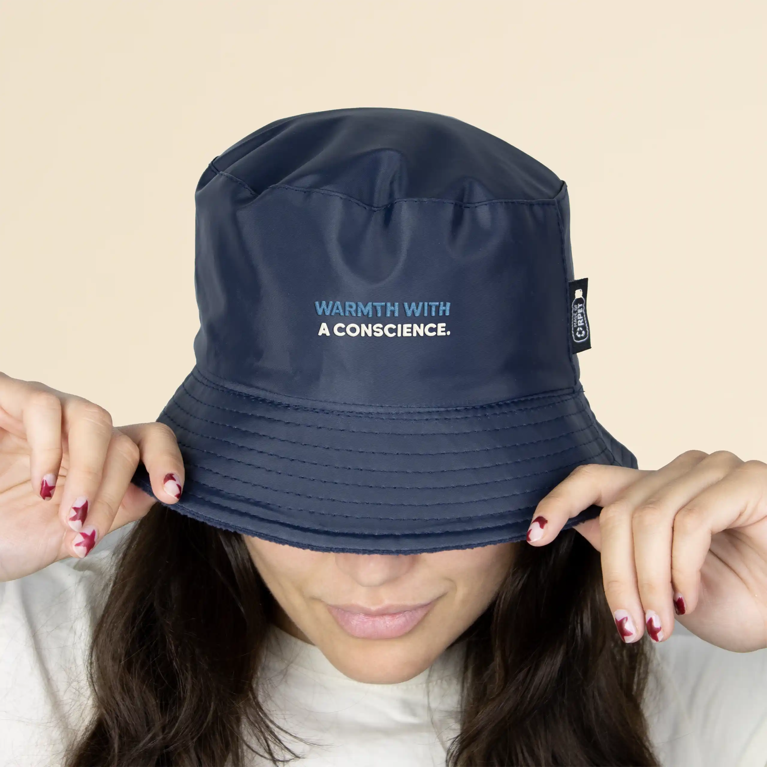 Chica con un gorro azul impermeable reversible ecológico sobre un fondo beige