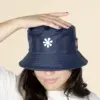 Chica con un gorro azul impermeable reversible ecológico sobre un fondo beige