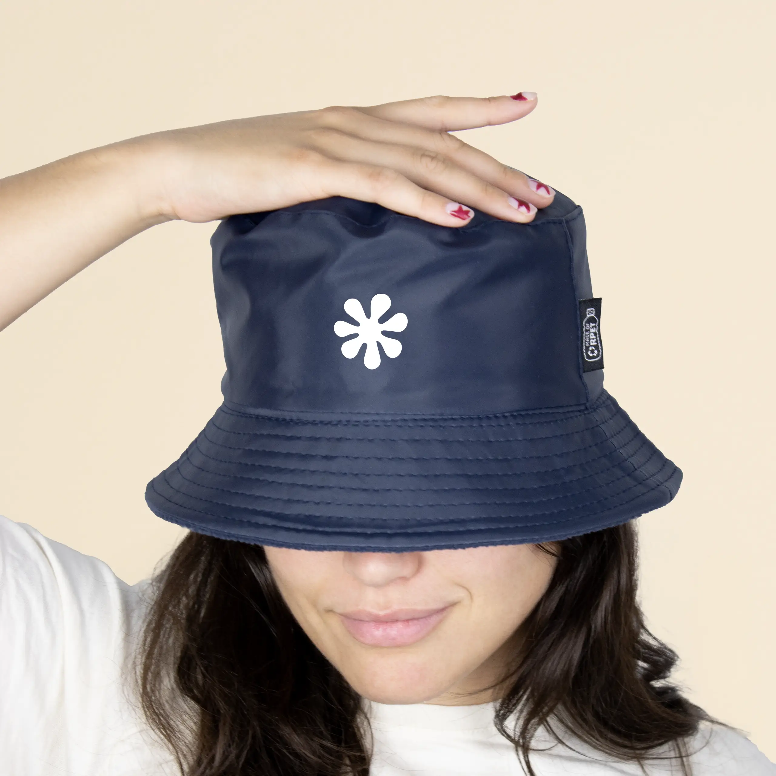 Chica con un gorro azul impermeable reversible ecológico sobre un fondo beige