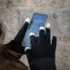 Chica usando el teléfono con guantes personalizados KLEAN
