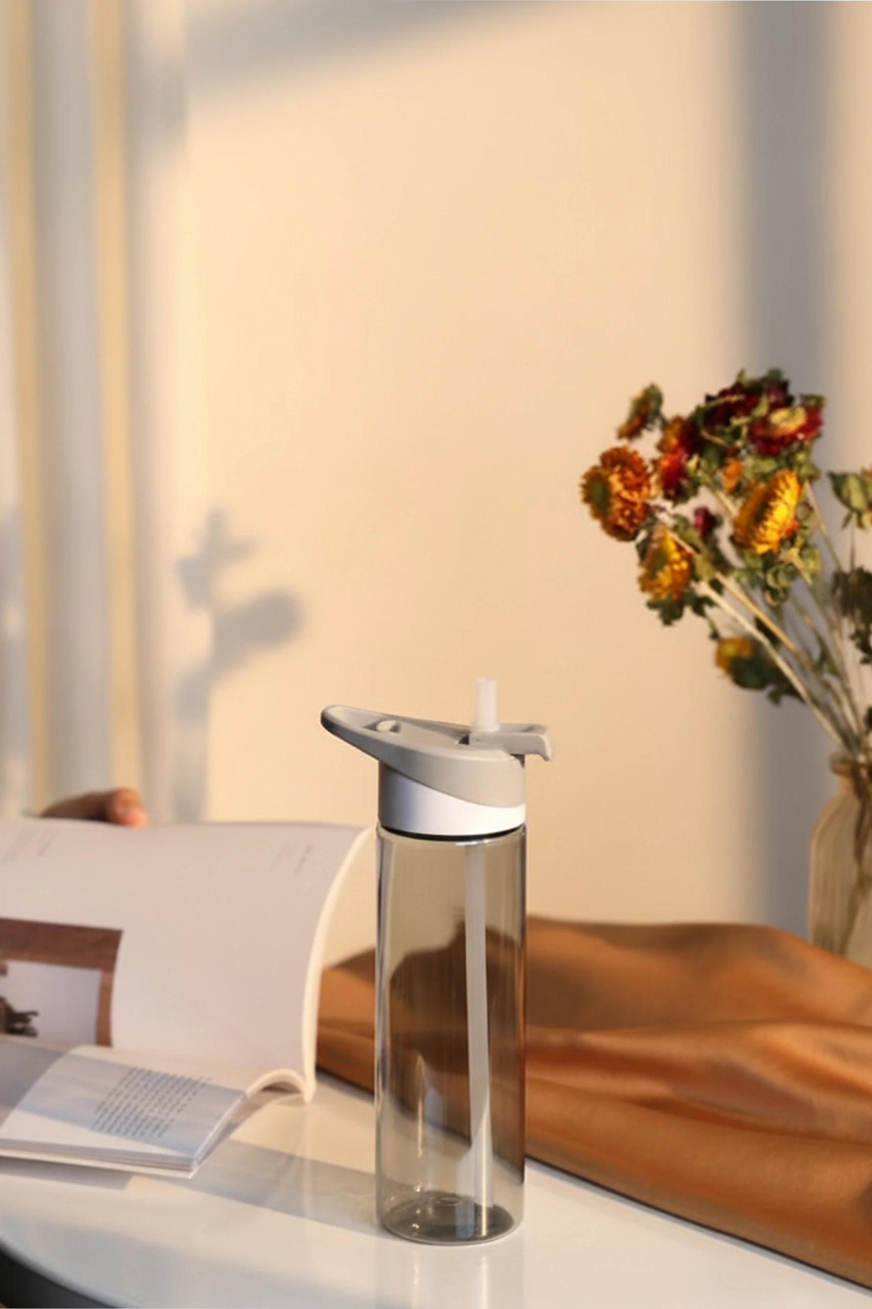 Botella de gimnasio gris sobre una mesa y un libro abierto