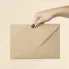 Mano mostrando la trasera de un sobre kraft en formato C5