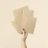 Mano sujetando cuatro sobres kraft de diferentes tamaños